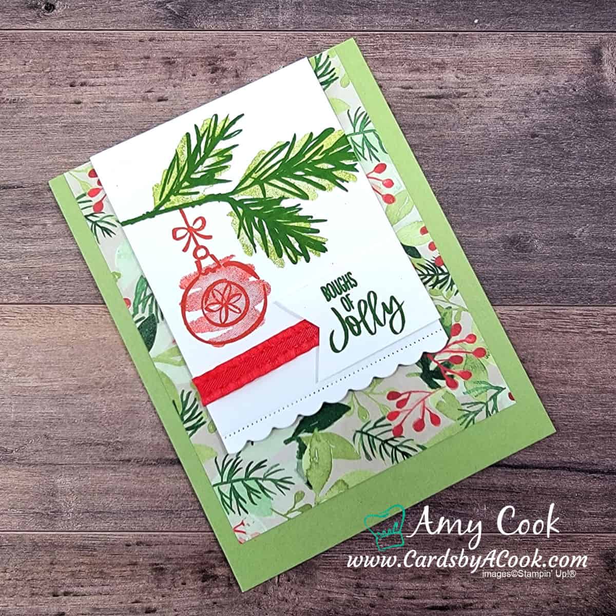 Christmas card featuring a Christmas tree branch hung with a red. Greeting reads Boughs of Jolly